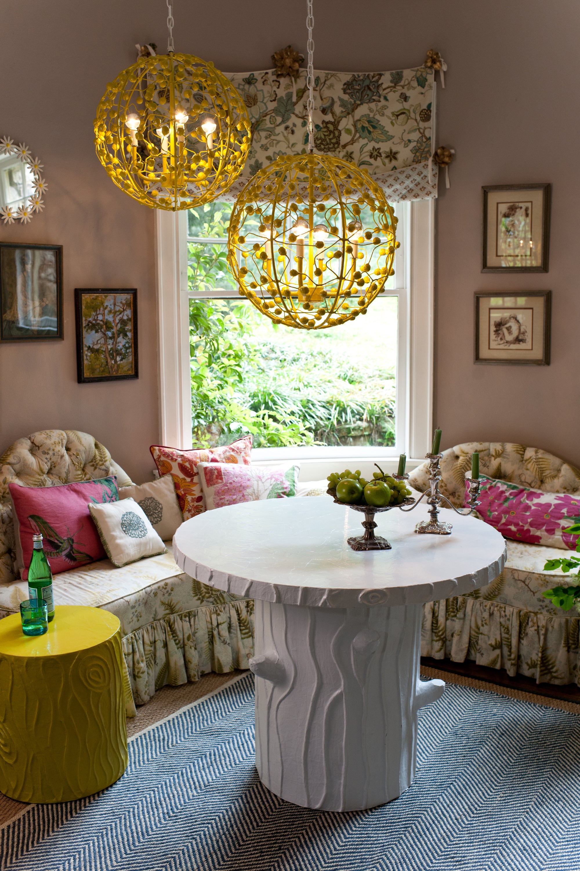 Living room with yellow pendant light, celester sphere by stray dog designs, floral sofa, and decorative table.