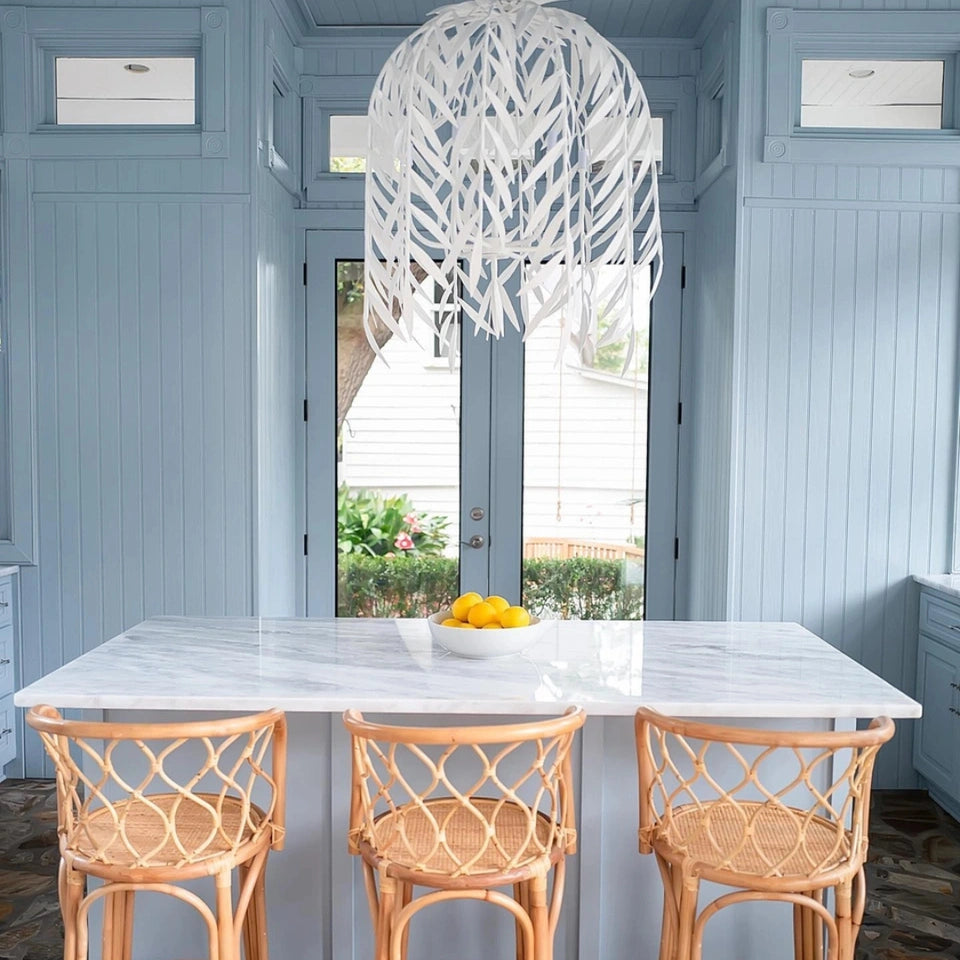 Stray Dog Designs Willow Chandelier hanging over a marble counter top with bamboo bar chairs in a kitchen bathed in a muted light blue paint color. 

Gray Benko Home, Interior Design Inspiration, luxury lighting, coastal aesthetic, kitchen inspiration
