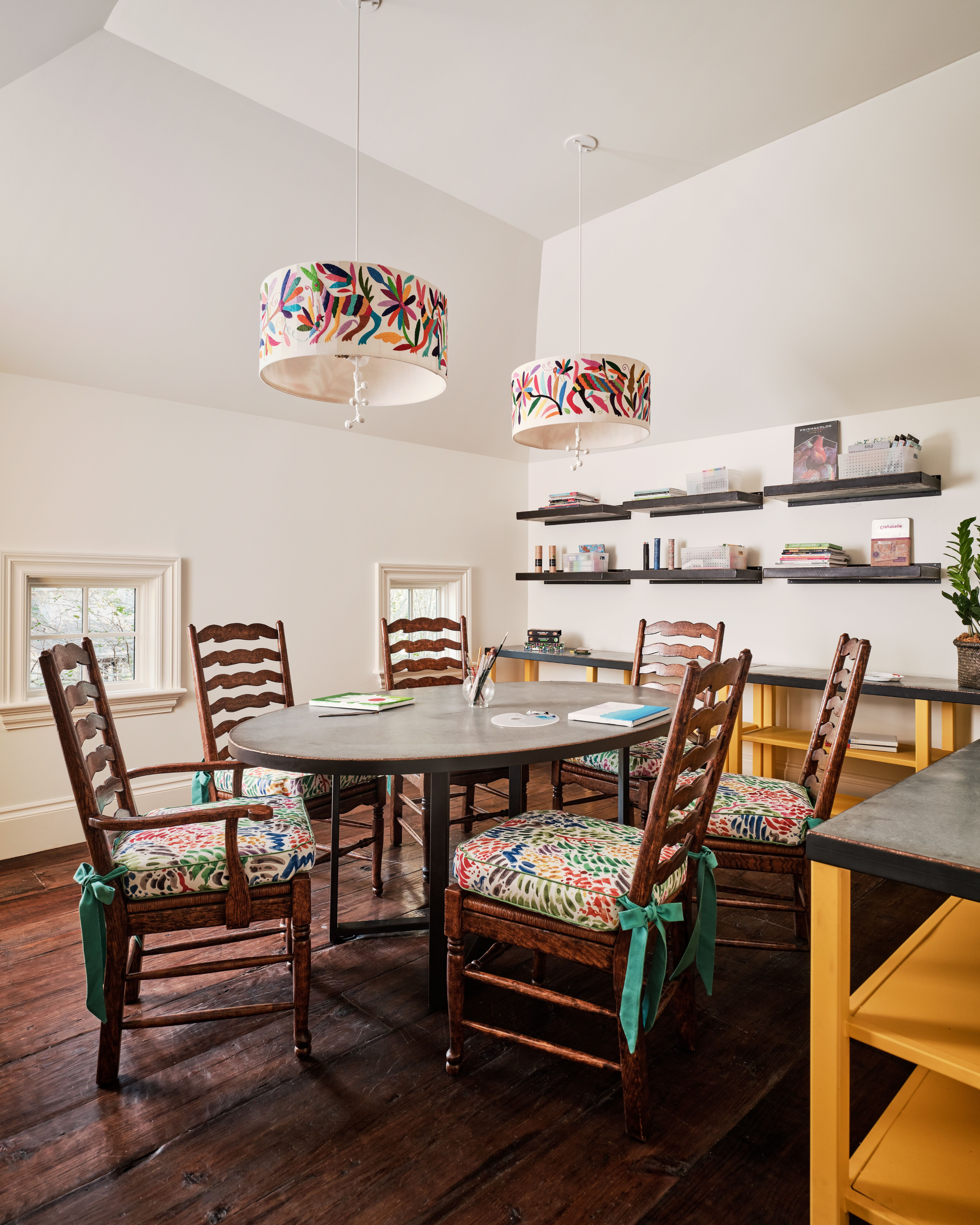 Dining room with wooden chairs, a round table, and colorful lampshades. Featuring the Otomi Pendant